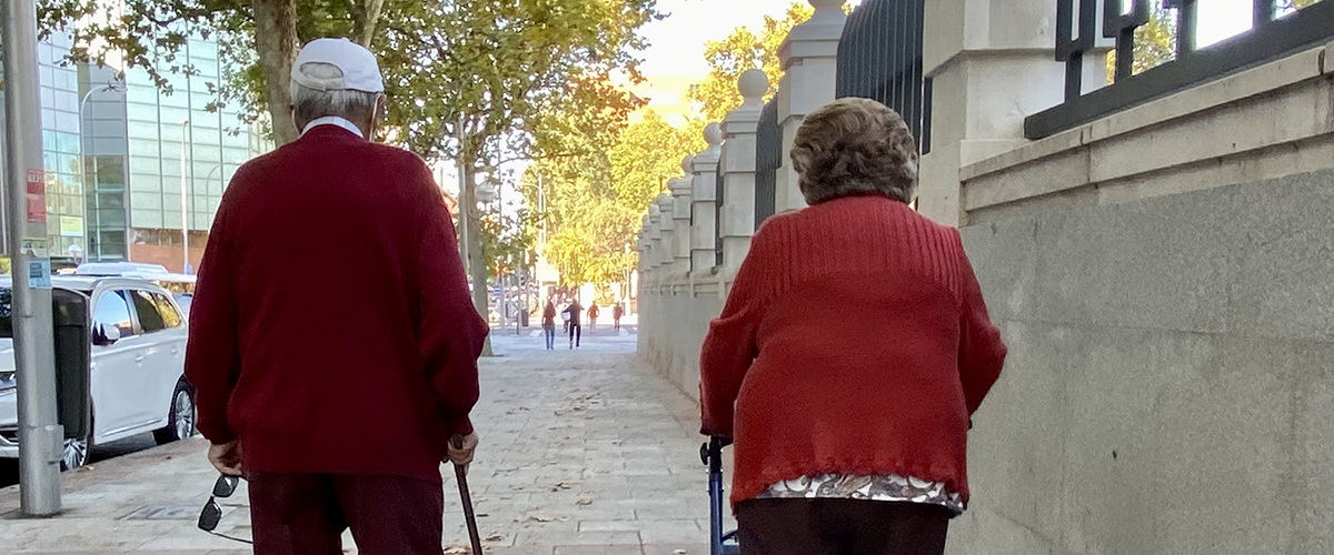 Dos pensionistas caminan de espaldas por una calle de Madrid
