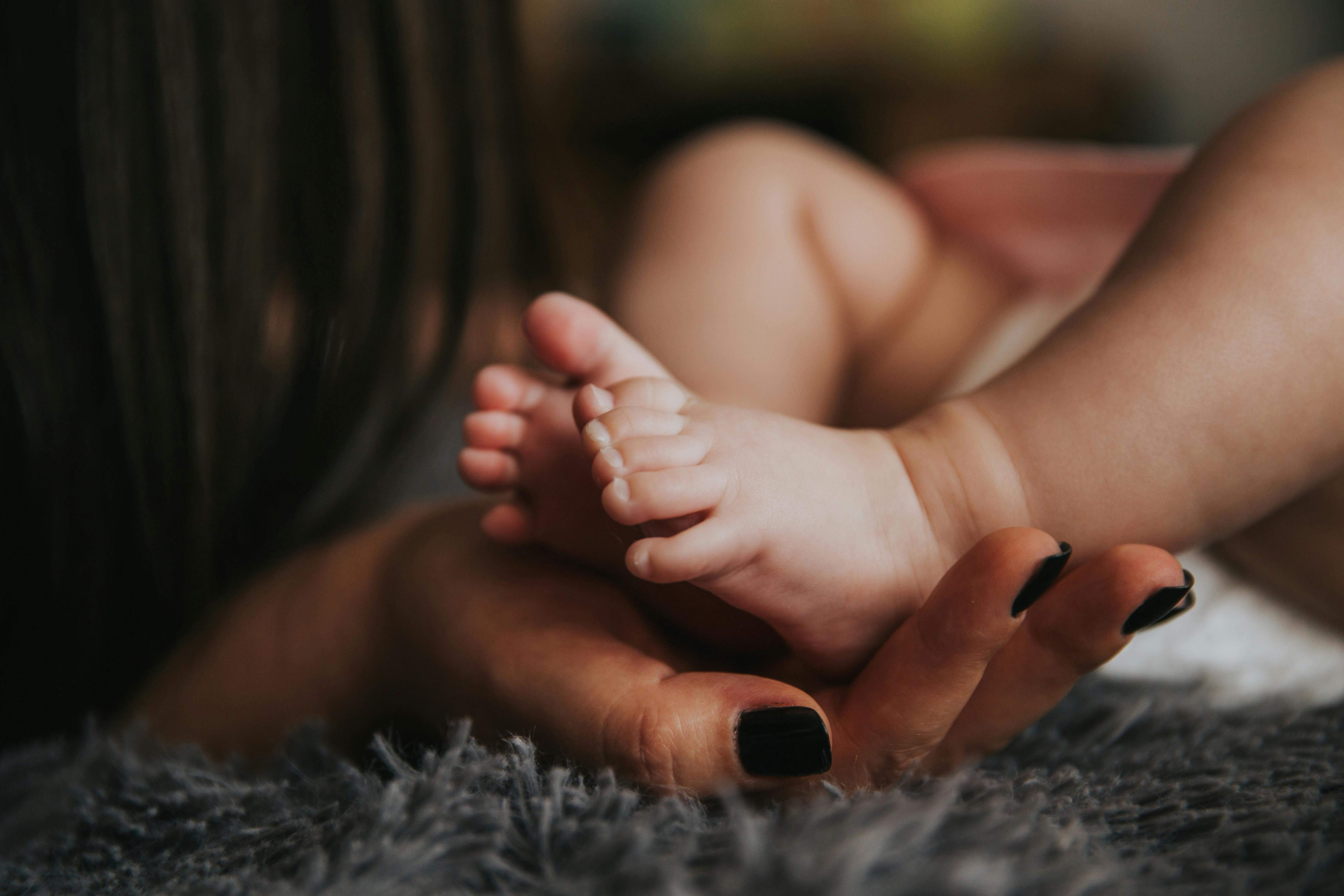 Madre sosteniendo los pies de su bebé recién nacido