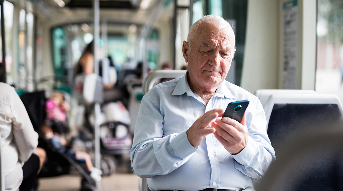 Pensionista consulta su móvil en el autobús