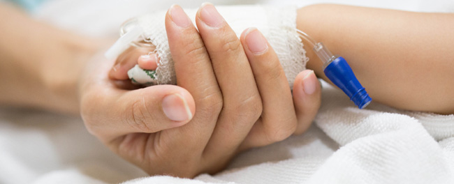 Recovering Little Child Lying in the Hospital Bed Sleeping, Mother Holds Her Hand Comforting. Focus on the Hands. Emotional Family Moment.