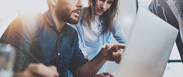 Group of coworkers sitting at the wooden table and working together on new startup project in modern loft office.Horizontal.Blurred background.Cropped.