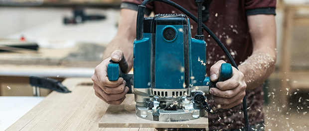 Manual wood concept. Cropped close up photo of cabinetmaker handcraft tradesman with electric tool in hands make furniture in garage or workroom