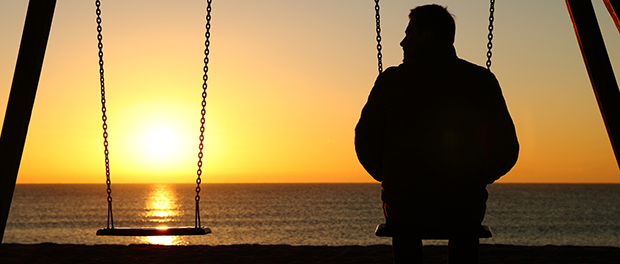 Man alone on a swing looking at empty seat