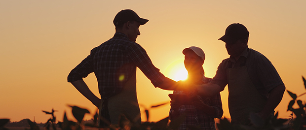 A group of farmers in the field, shaking hands. Family Agribusiness