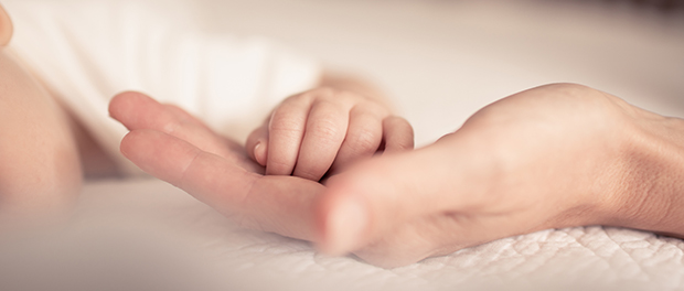 Mother holding tiny little newborn baby hand in hers
