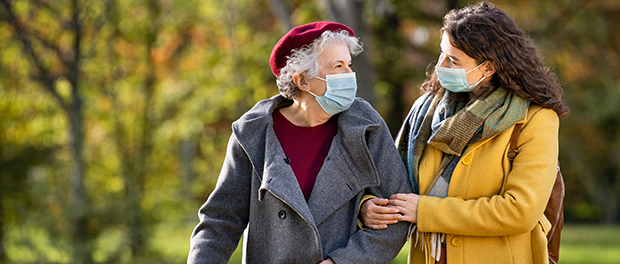 Senior woman with lovely girl wearing face mask at park