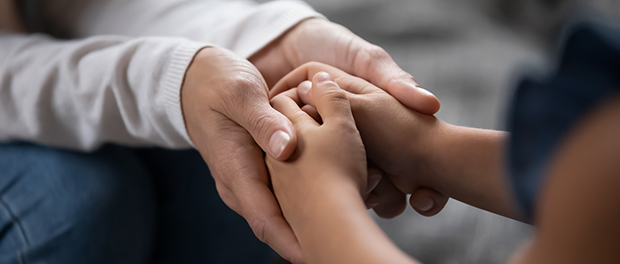 Madre sostiene las manos de su hija